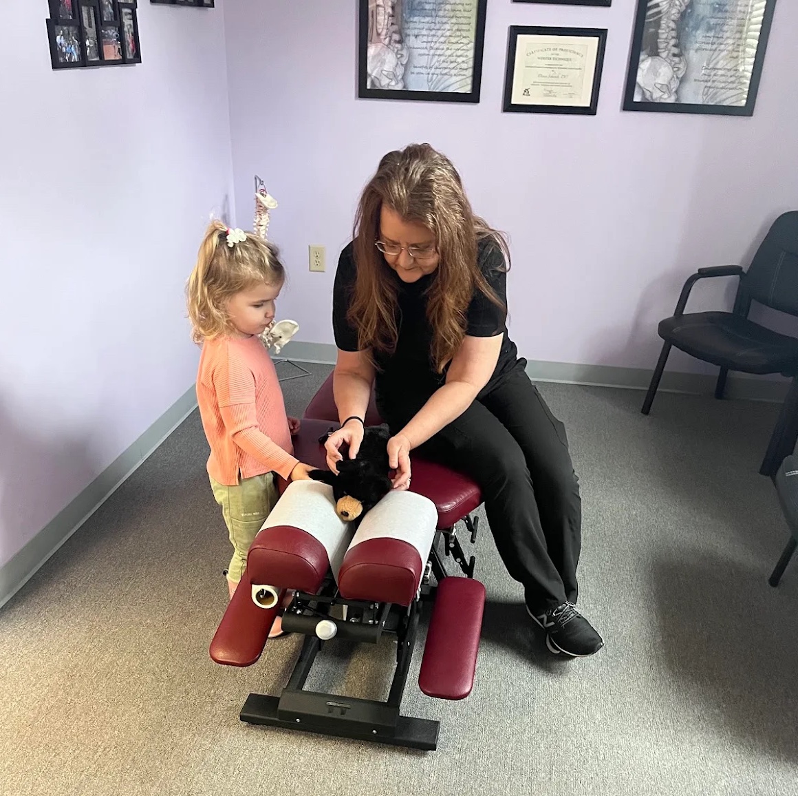 Dr Schwab giving a child's teddy bear a chiropractic adjustment.